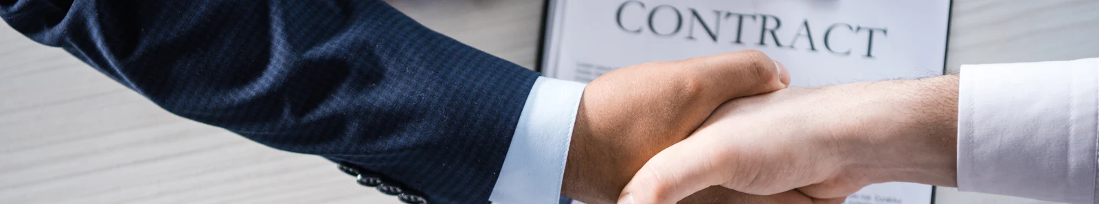Picture of hands shaking in front of a contract